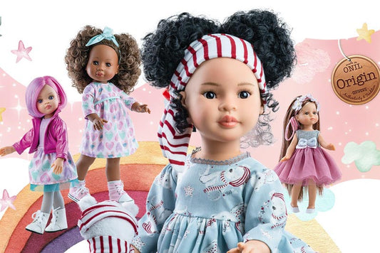 A collection of Paola Reina dolls dressed in stylish outfits, featuring different hairstyles, skin tones, and accessories.