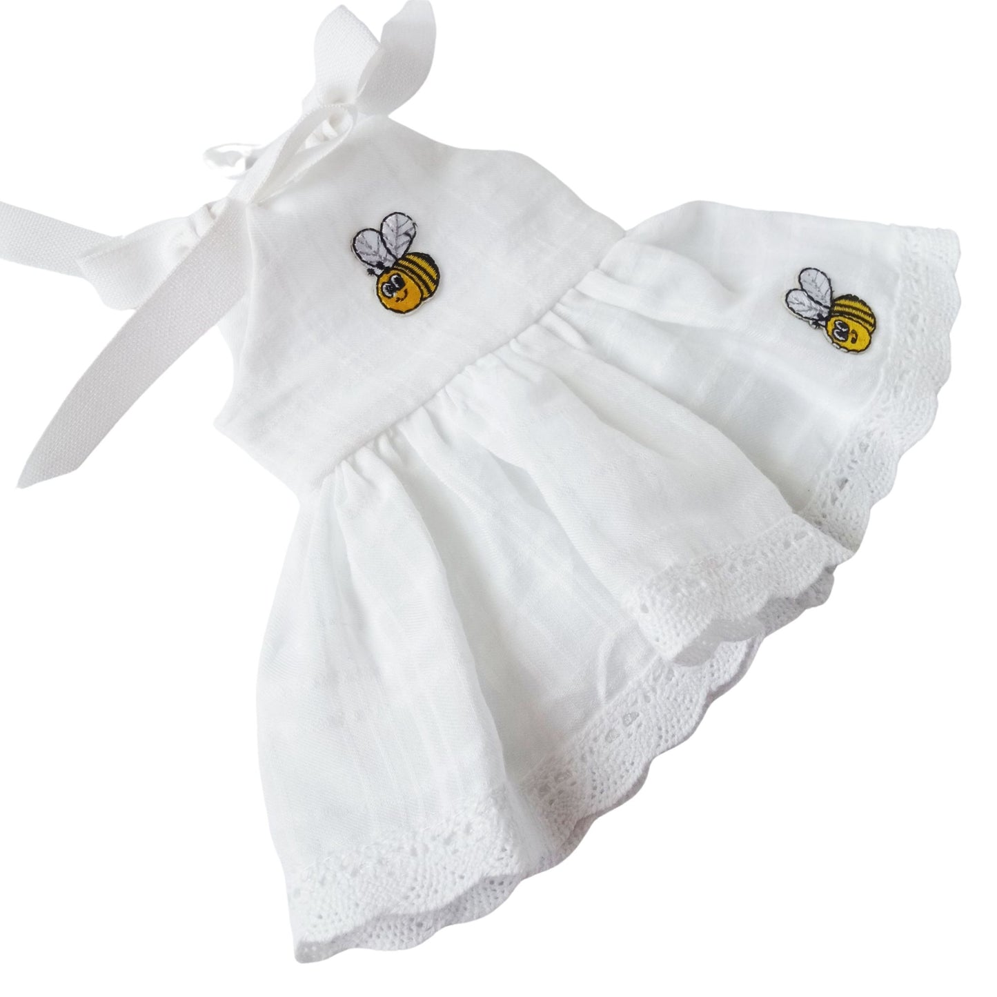 A white cotton sundress with embroidered bees, lace trim, and tied shoulder straps, accessorized with a matching bow headband, fits 34 cm dolls like Paola Reina or Baby Born