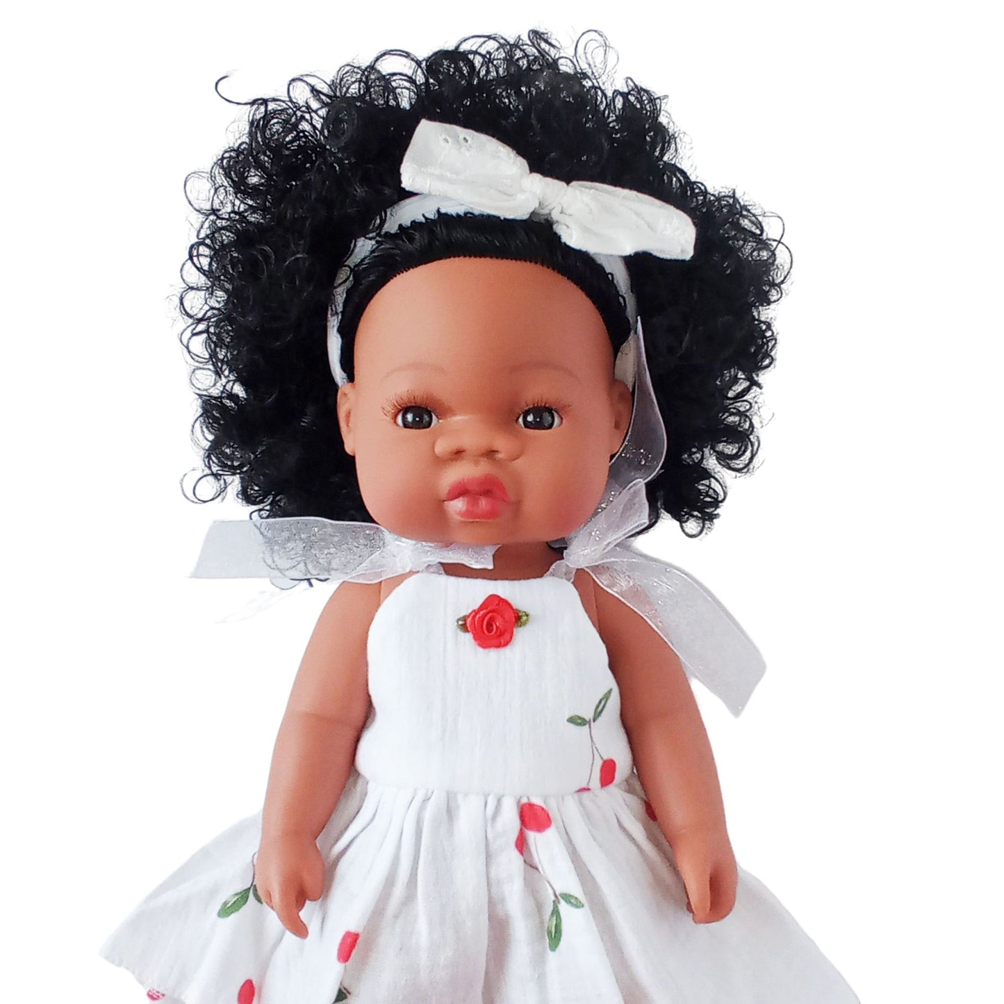 Dark-skinned curly-haired doll wearing a white summer cotton sundress with cherry print and red rose detail, designed for 34 cm dolls like Paola Reina or Baby Born.