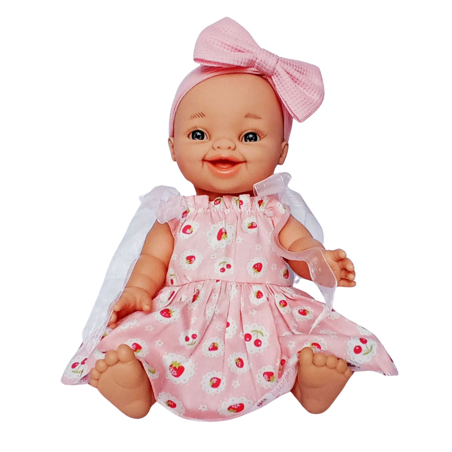 Smiling doll in pink strawberry print cotton sundress with white ribbon sleeves and pink bow headband, perfect for 34 cm Paola Reina or Baby Born dolls.