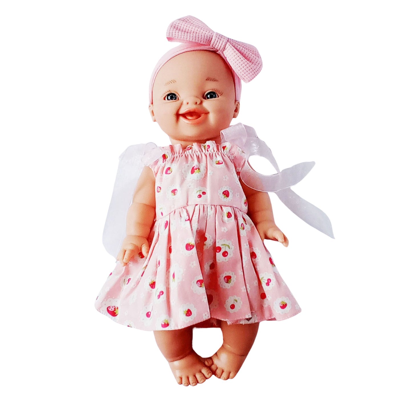 Smiling doll in pink strawberry print cotton sundress with white ribbon sleeves and pink bow headband, perfect for 34 cm Paola Reina or Baby Born dolls.