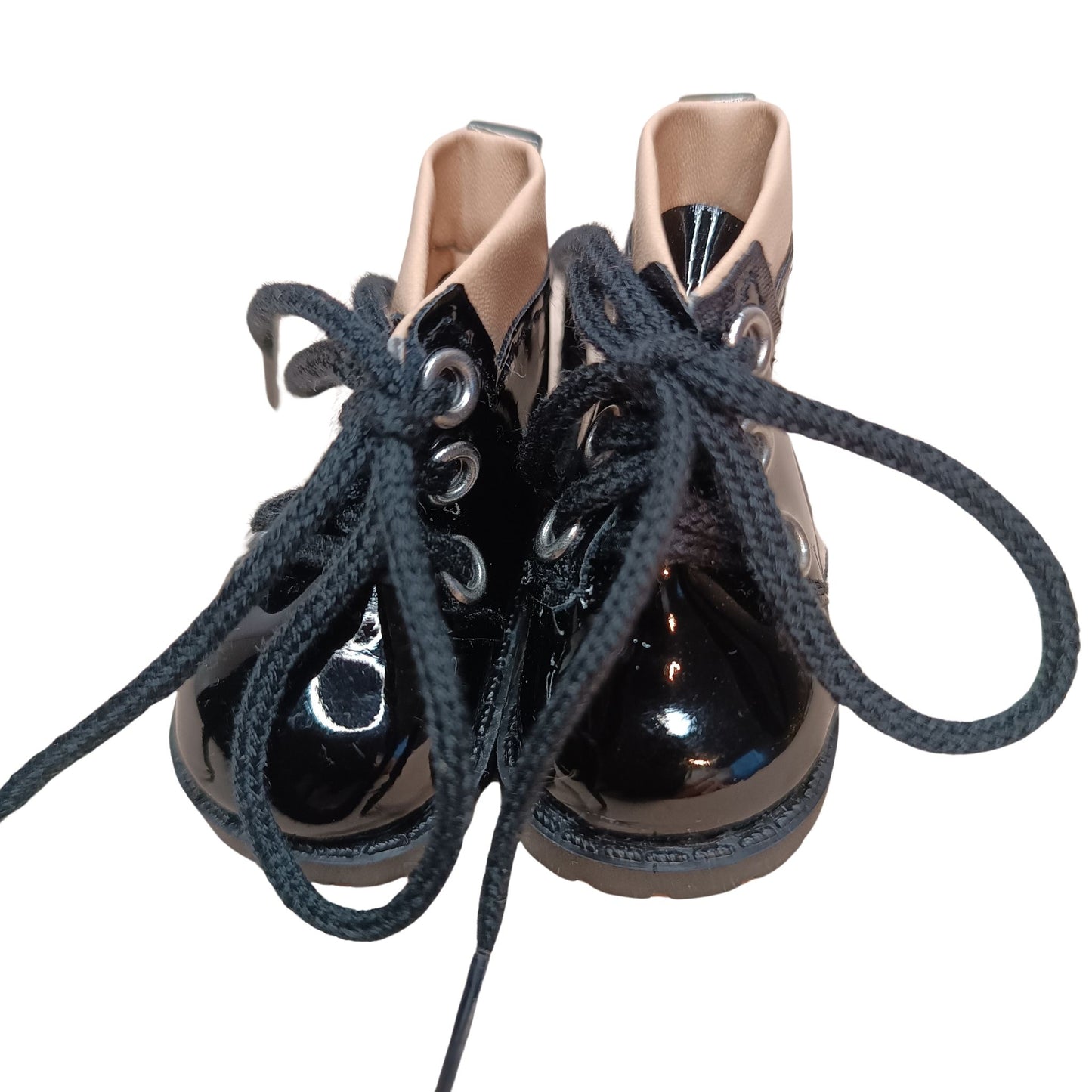 Glossy black lace-up boots with beige cuffs, designed for 32 cm Paola Reina dolls. Featuring black laces, metal eyelets, and a chunky sole for a bold fashion statement.