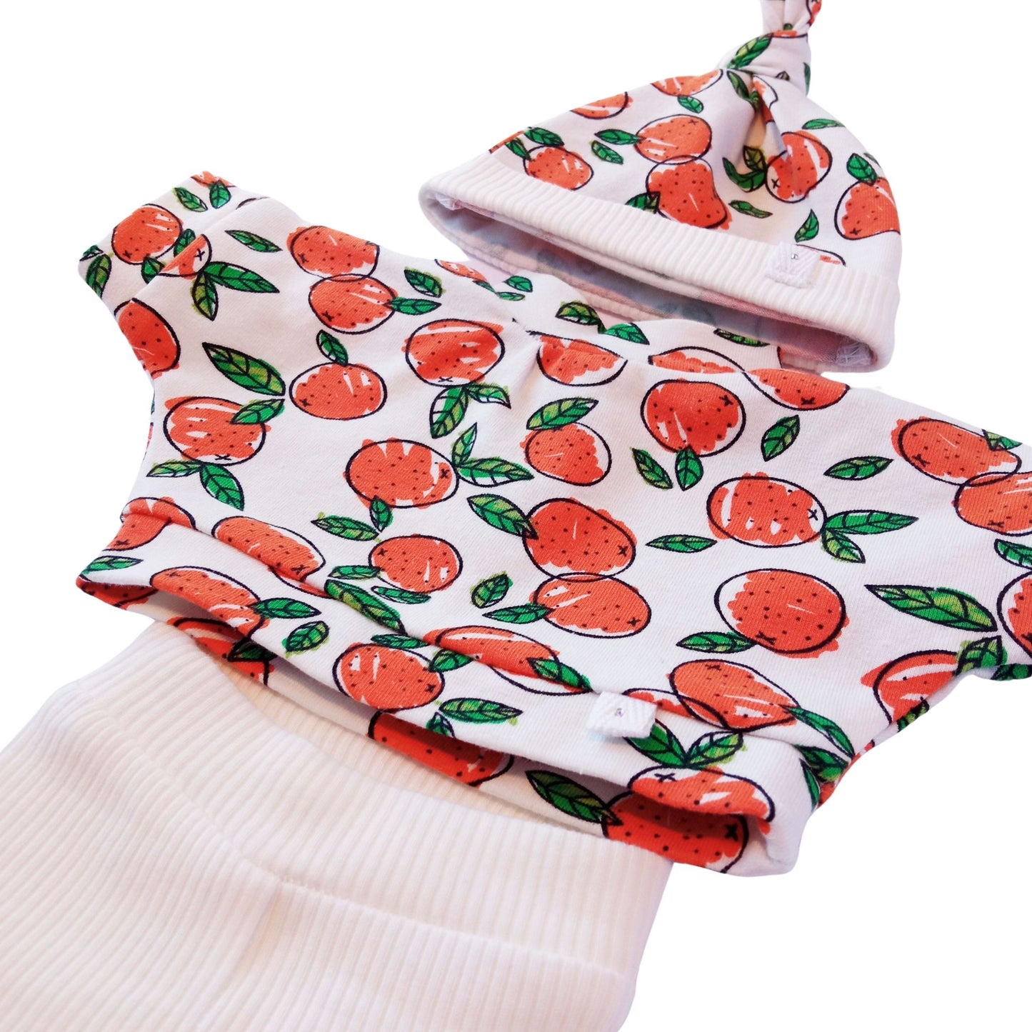 A 3-piece knit outfit with orange fruit print blouse, white ribbed pants, and a matching citrus-themed hat – fits Paola Reina and Baby Born 34 cm dolls.