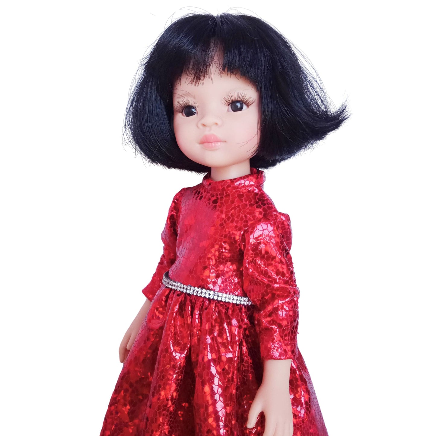 Paola Reina 32 cm doll wearing a red sparkling dress with a rhinestone belt and black patent leather shoes, standing against a white background.