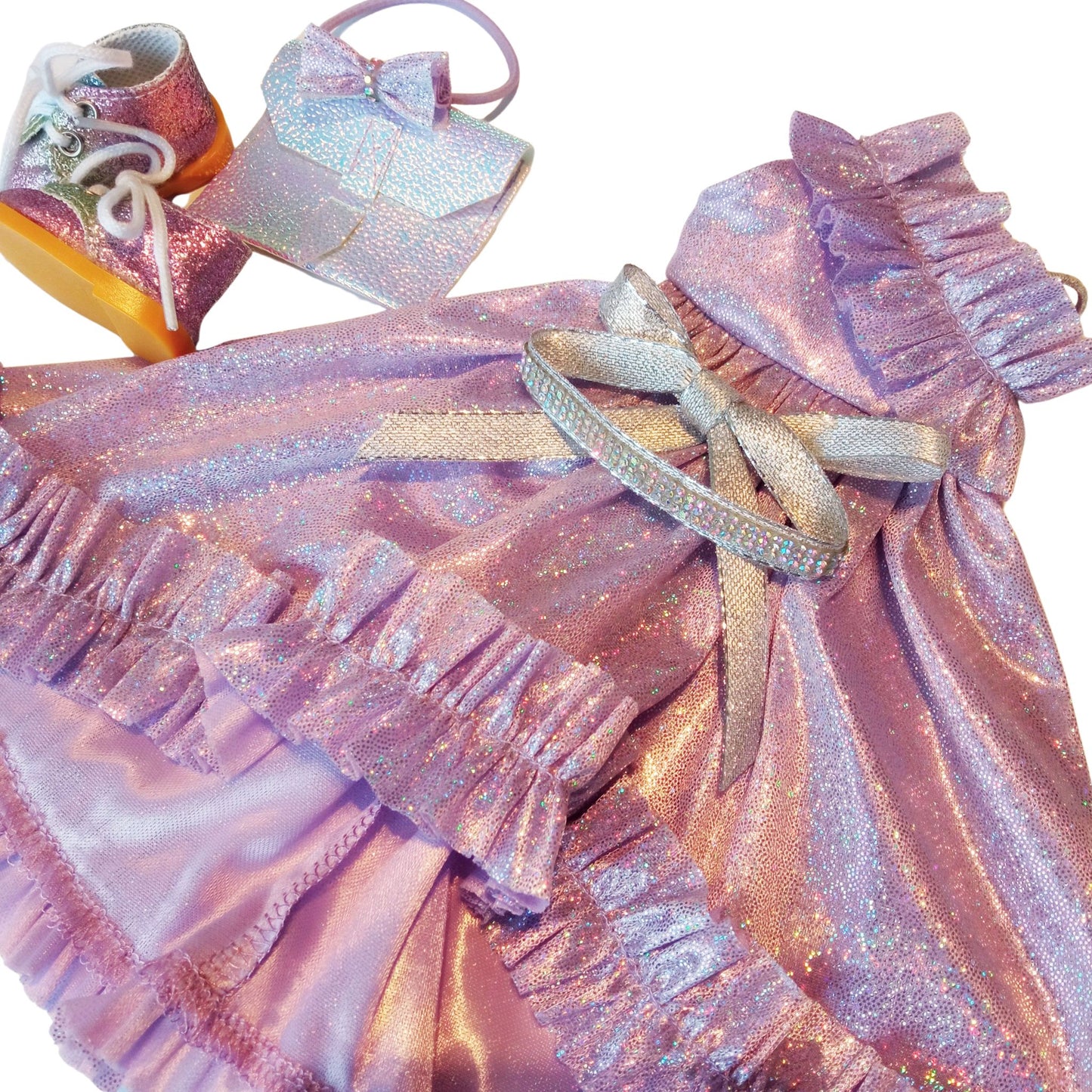 Doll wearing a lilac dress with ruffles, matching headband, holographic clutch, and glitter sneakers for doll Paola Reina 32 cm.