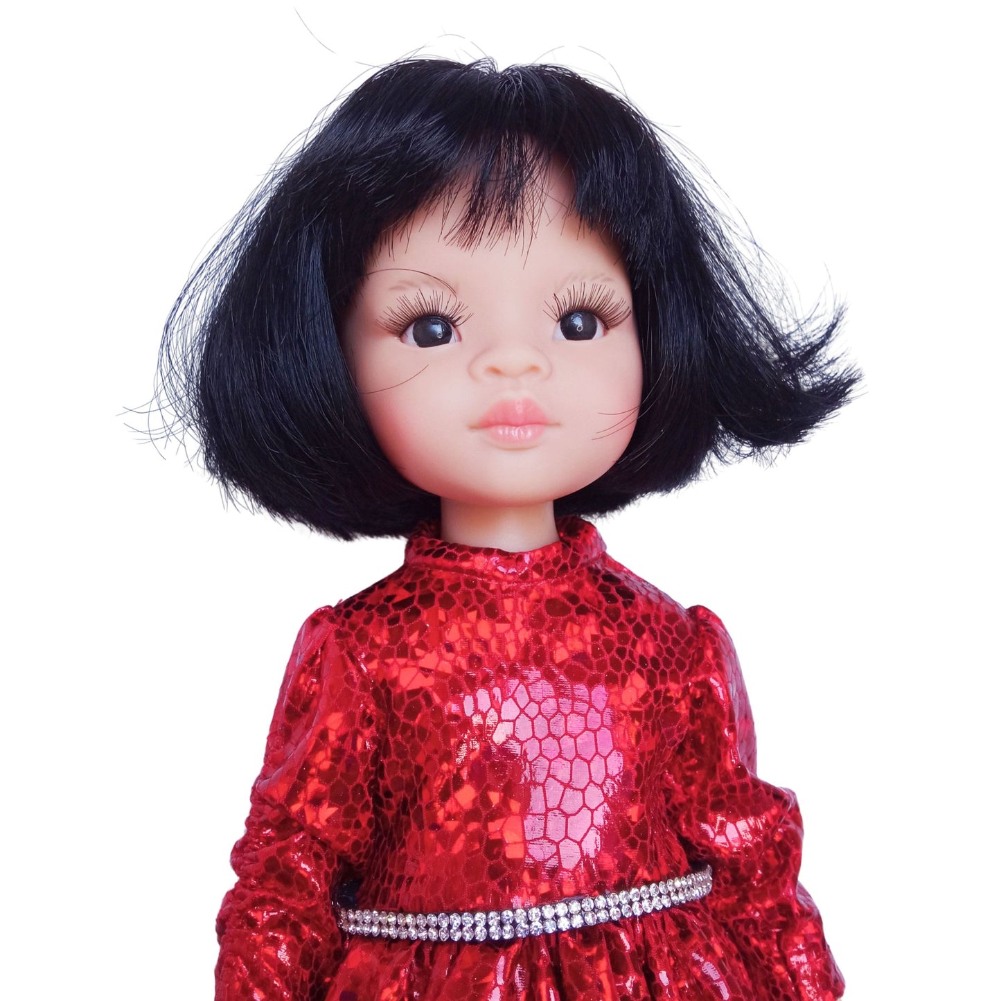 Paola Reina 32 cm doll wearing a red sparkling dress with a rhinestone belt and black patent leather shoes, standing against a white background.