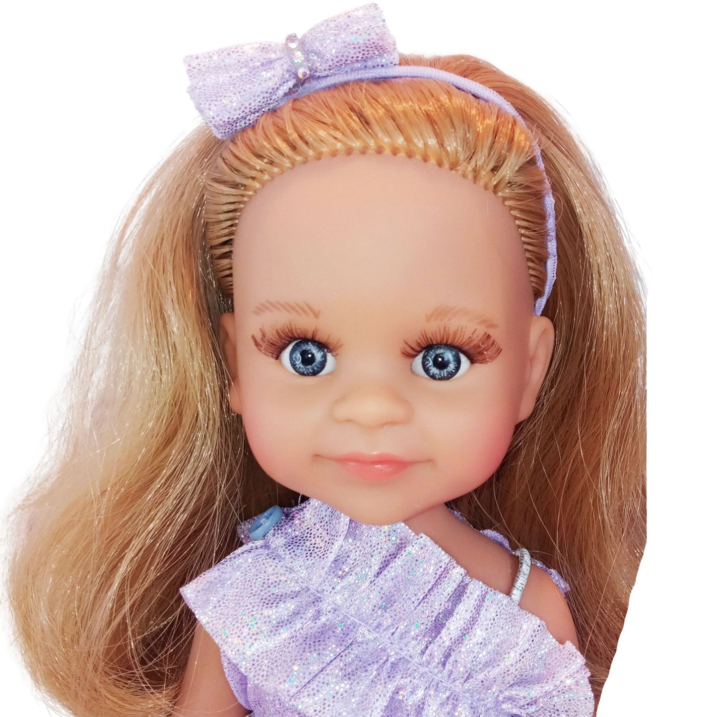 Paola Reina 32 cm doll wearing a lilac dress with ruffles, matching headband, holographic clutch.