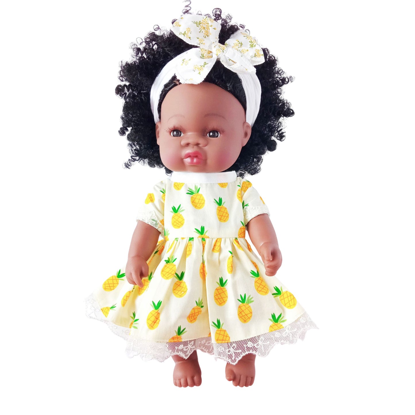 Doll wearing a yellow summer dress with pineapple print and lace hem, paired with a matching headband with bow, suitable for 34 cm dolls like Paola Reina or Baby Born