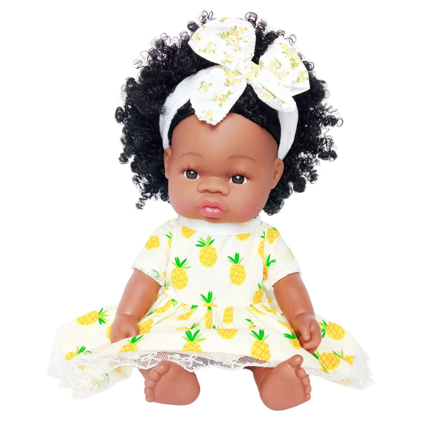 Doll wearing a yellow summer dress with pineapple print and lace hem, paired with a matching headband with bow, suitable for 34 cm dolls like Paola Reina or Baby Born.