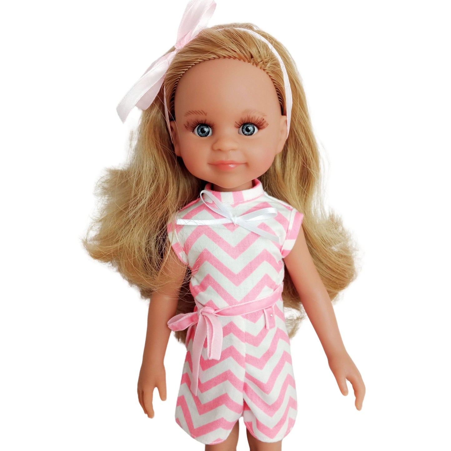 Paola Reina 32 cm doll wearing a pink and white zigzag summer jumpsuit with a ribbon belt and matching headband.
