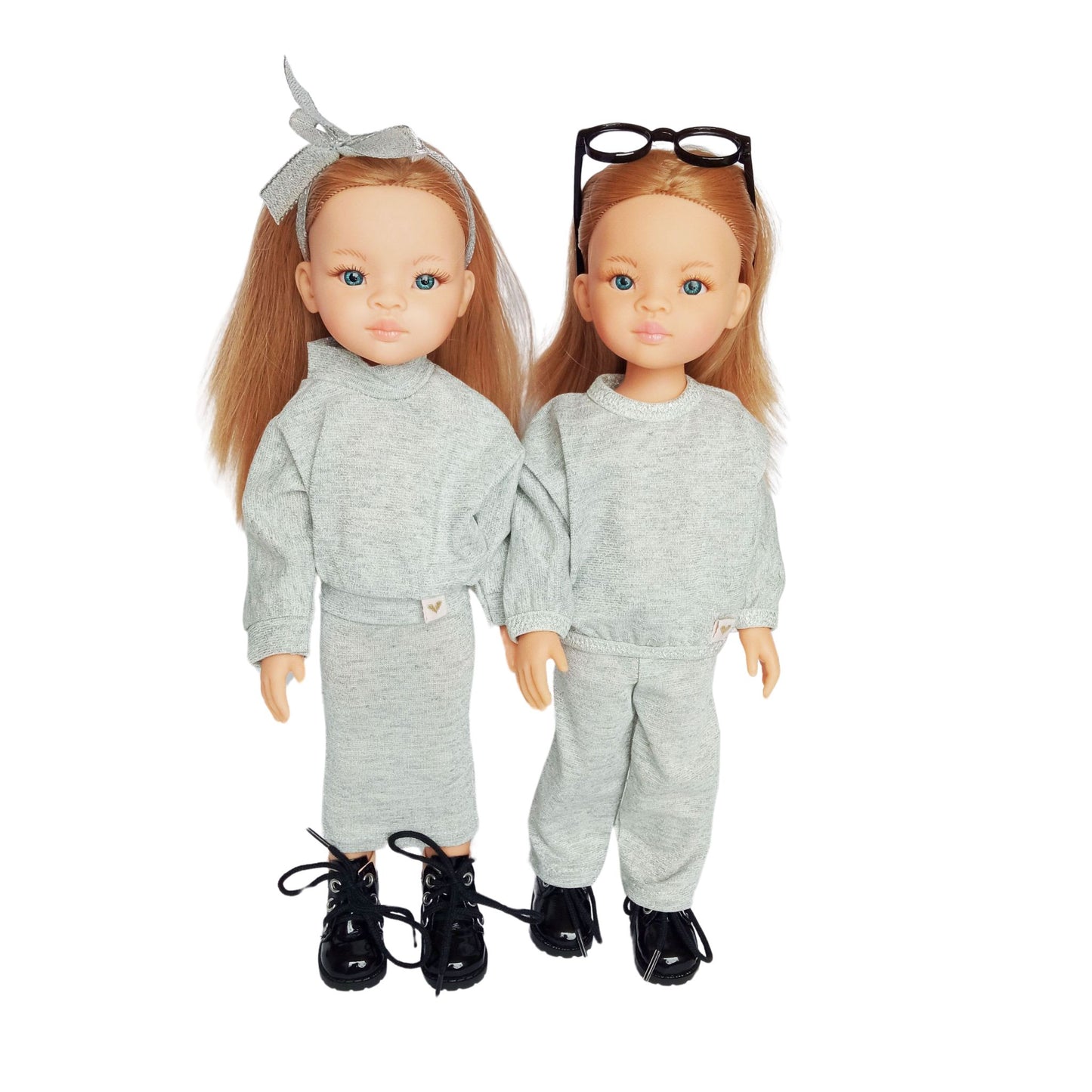 Two Paola Reina dolls wearing stylish shimmer jersey sets – one with a skirt, the other with pants – paired with black sneakers and cute accessories.