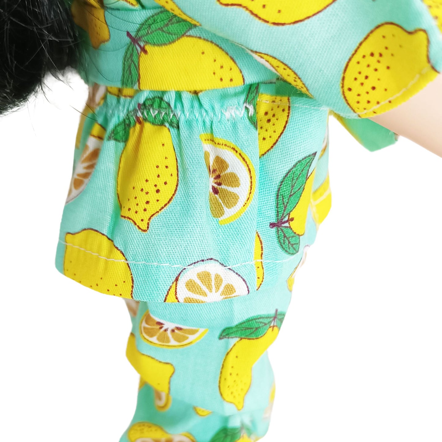 Paola Reina 32 cm doll wearing a bright lemon-printed jumpsuit with a matching belt, standing in yellow boots, styled for a cheerful summer look.