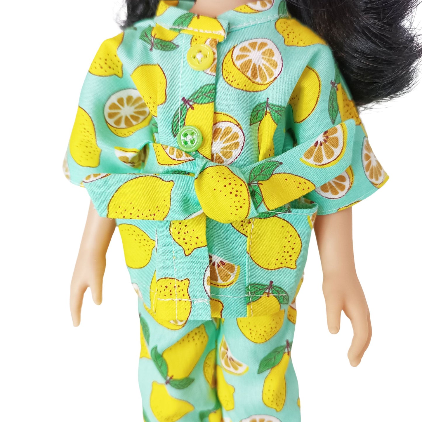 Paola Reina 32 cm doll wearing a bright lemon-printed jumpsuit with a matching belt, standing in yellow boots, styled for a cheerful summer look.