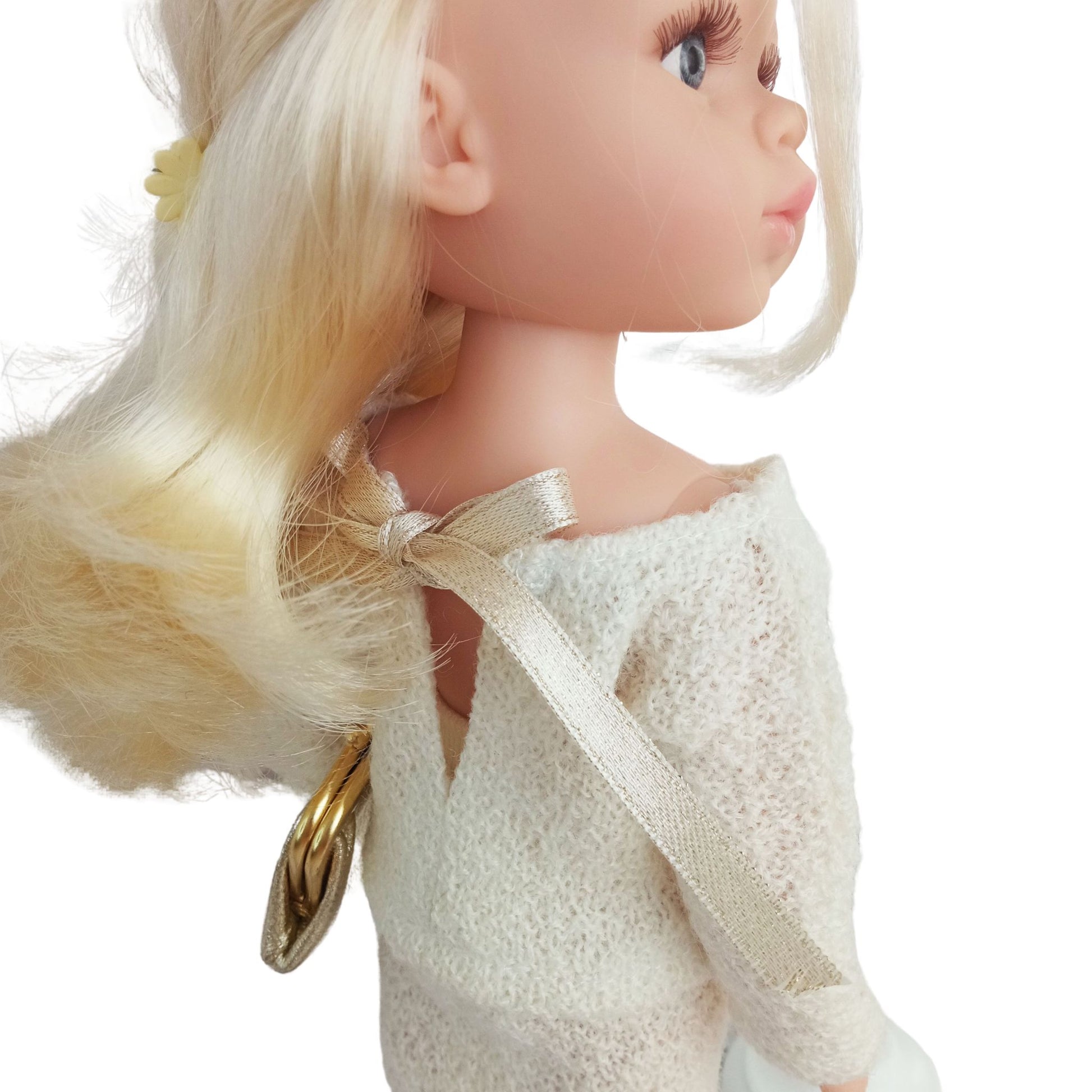 Paola Reina Las Amigas 32 cm doll dressed in a handmade knitted jersey outfit with a buttoned top, matching skirt, and a stylish belt, holding a gold clutch.