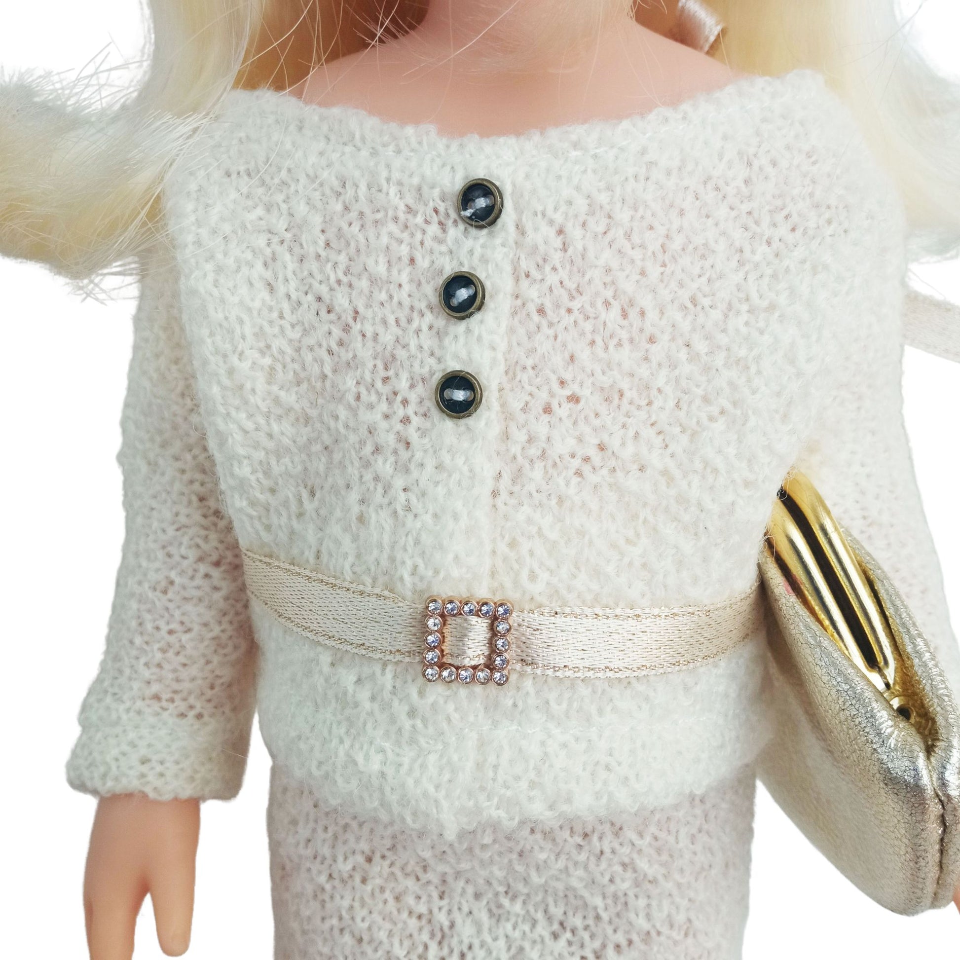 Paola Reina Las Amigas 32 cm doll dressed in a handmade knitted jersey outfit with a buttoned top, matching skirt, and a stylish belt, holding a gold clutch.