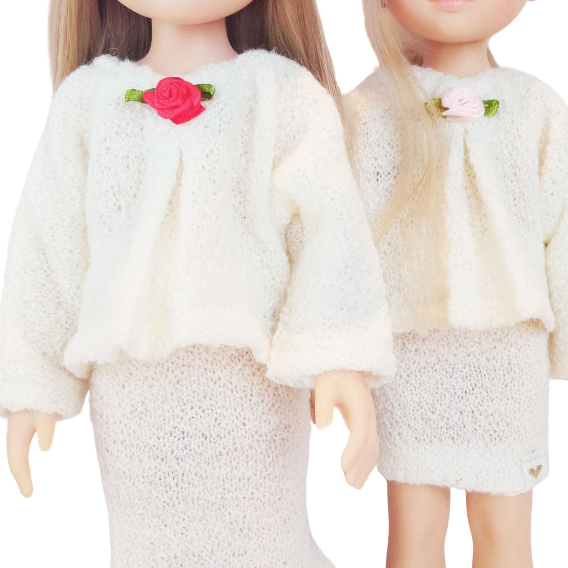 Two Paola Reina Las Amigas 32 cm dolls wearing handmade knitted jersey outfits with floral accents, featuring a top and matching skirt in two styles.
