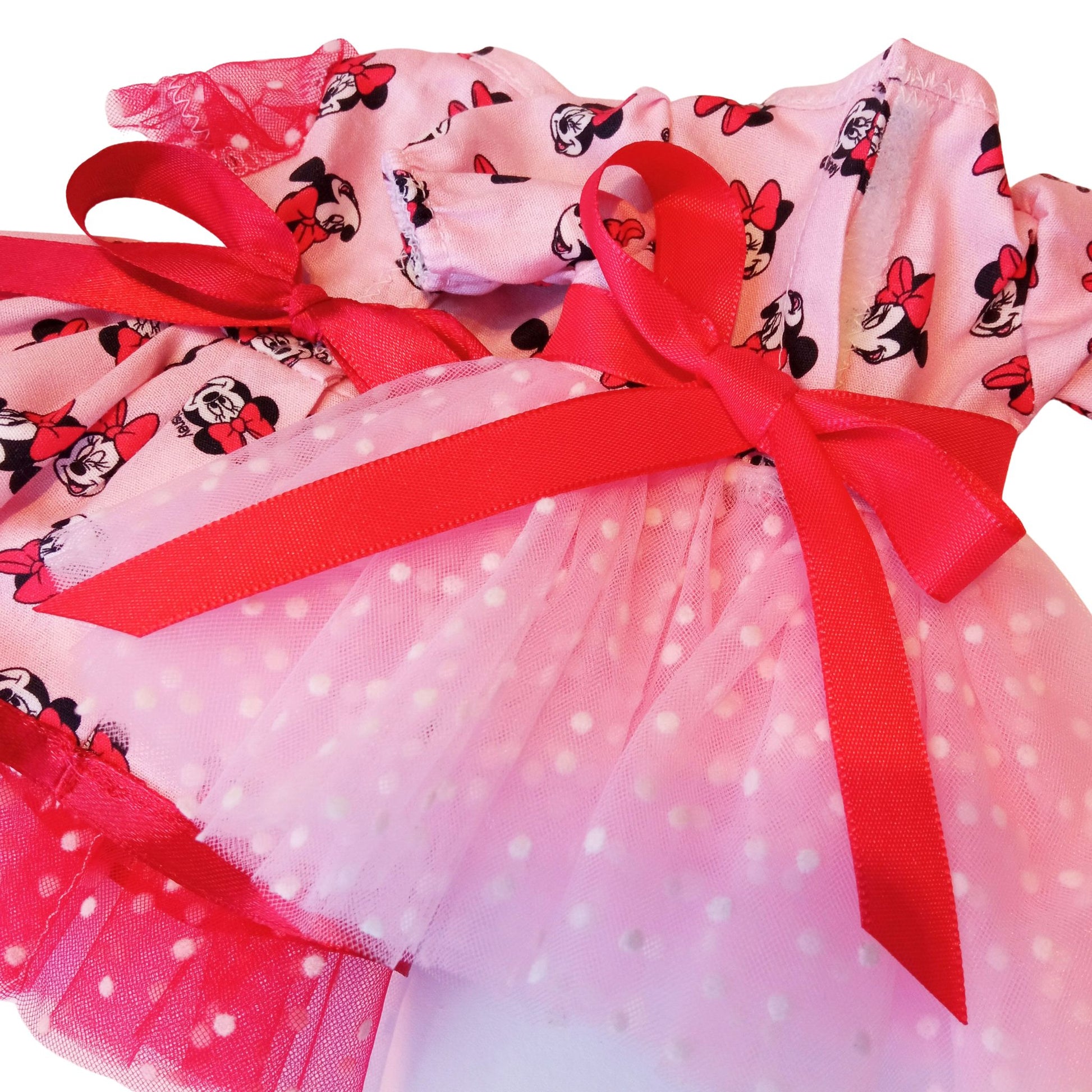 Two dress for Paola Reina 32 cm doll wearing matching Minnie Mouse-inspired dresses with red satin bows and polka-dot mesh details. 